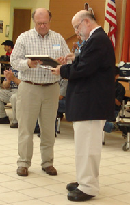 Mike Repinski (right) of CenturyLink renews the company's commitment to literacy with a donation to Literacy Partners' Mary Gotstein and Bob Garfinkel